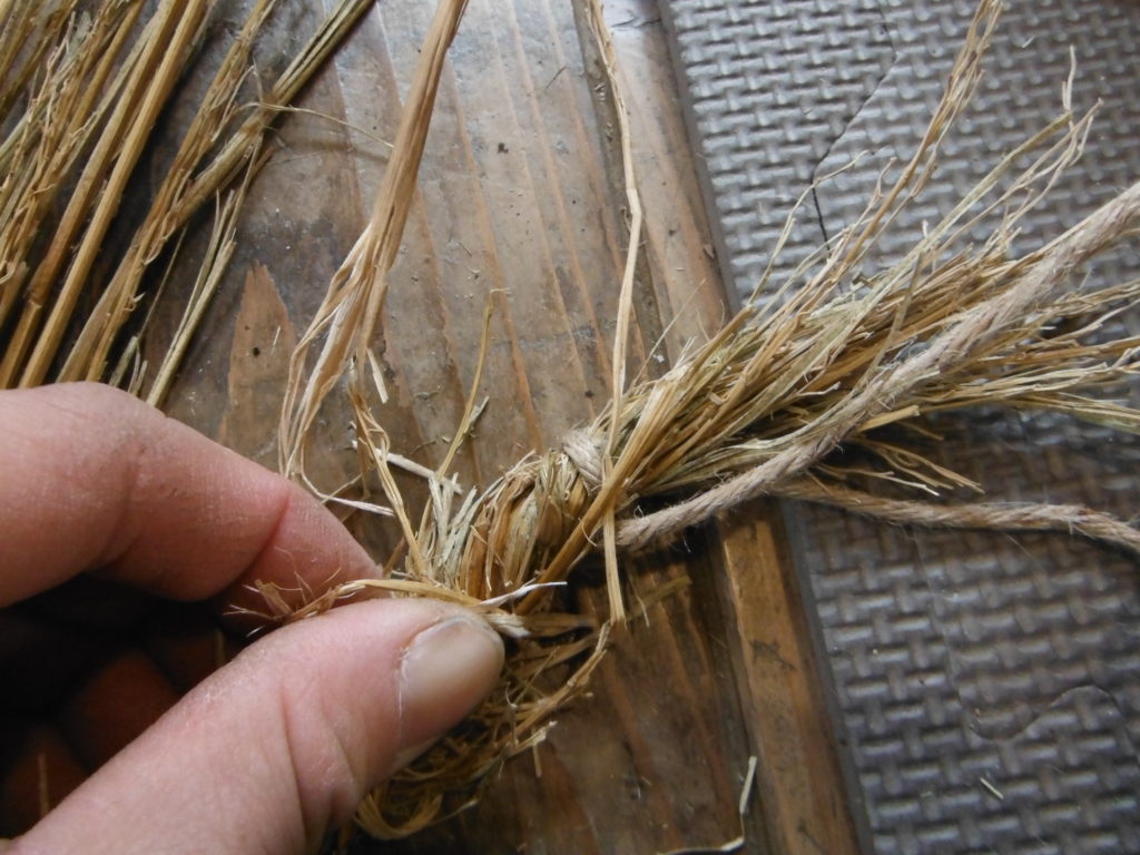 稲藁の束の先を麻ひもで結んでおく。