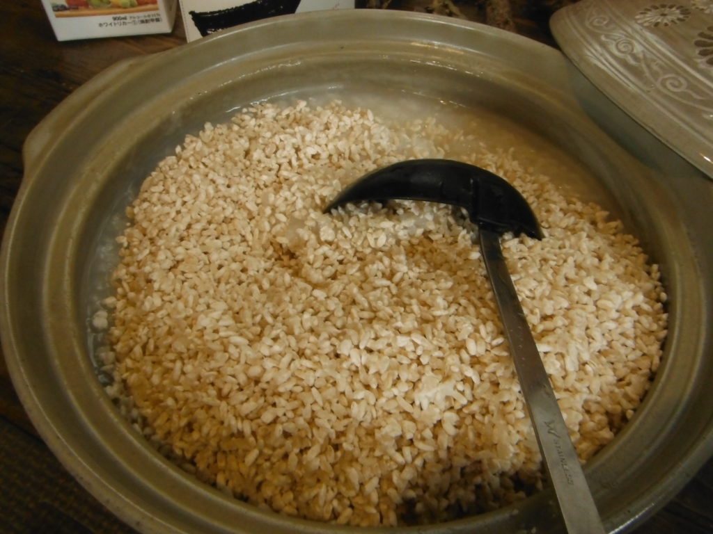 鍋にお粥と米麹が入って、お玉でかき混ぜている。