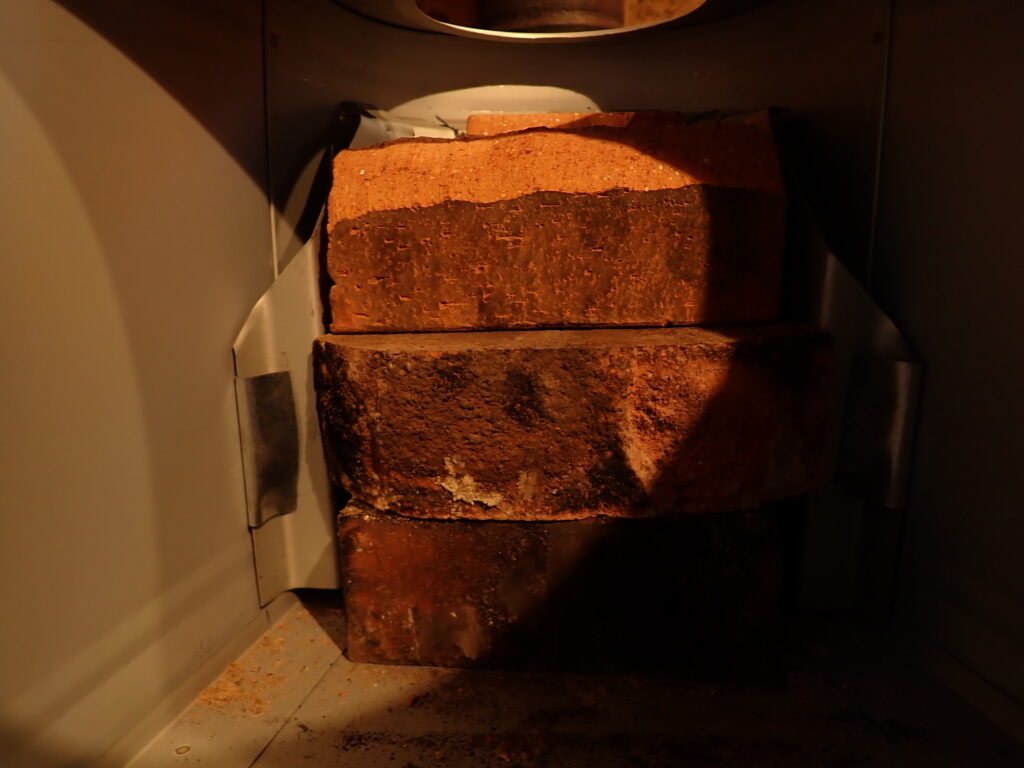 薪ストーブの内部にレンガを置いて、煙道を調整する
